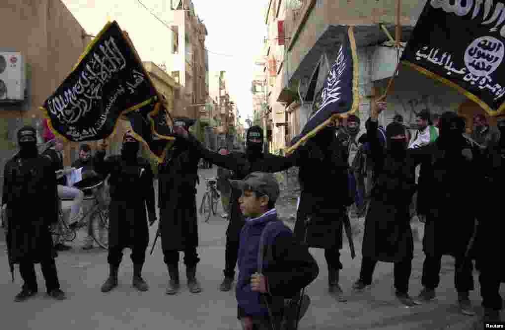 A boy walks past members of an Islamist group as they hold flags during a protest against Syrian President Bashar al-Assad's regime in Deir el-Zor, Syria, Feb. 25, 2013.