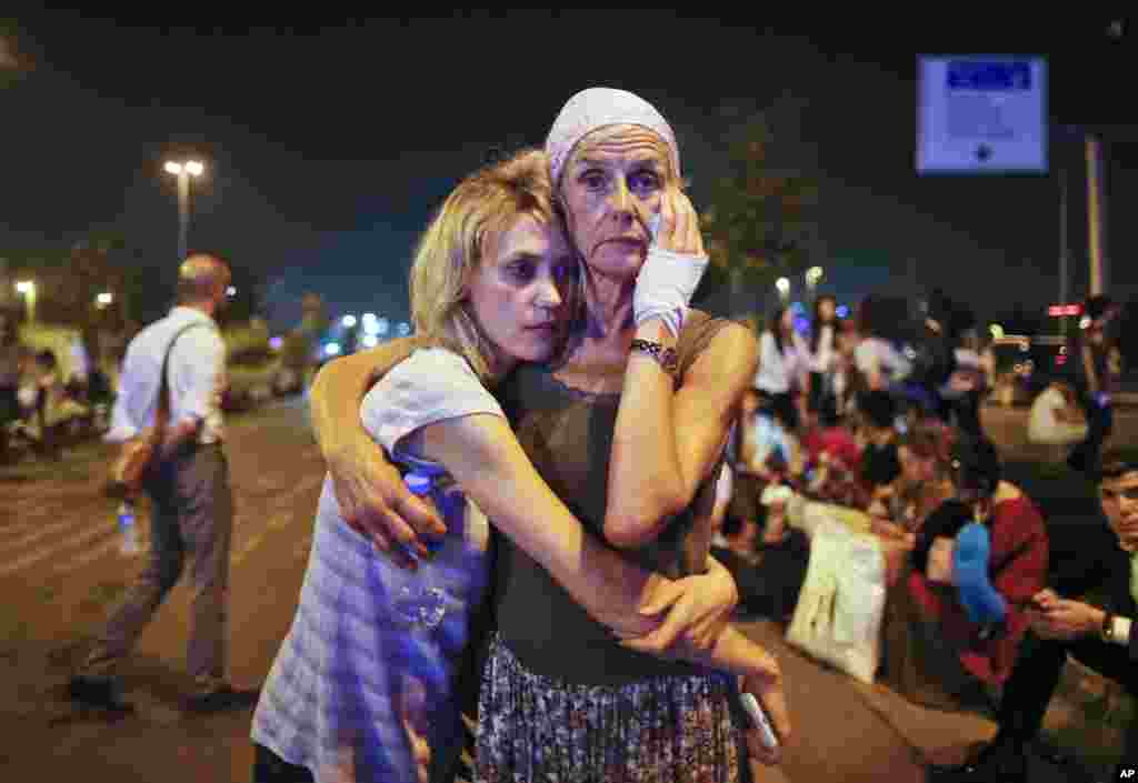 Passengers embrace each other early in the morning as they wait outside Istanbul's Ataturk airport following their evacuation in the wake of a number of explosions, June 29, 2016.