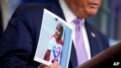 FILE - President Donald Trump holds a photo of LeGend Taliferro as he speaks at a news conference i at the White House, Aug. 13, 2020, in Washington.