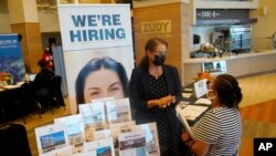 FILE - Marriott human resources recruiter Mariela Cuevas, left, talks to Lisbet Oliveros, during a job fair at Hard Rock Stadium, in Miami Gardens, Florida, Sept. 3, 2021.