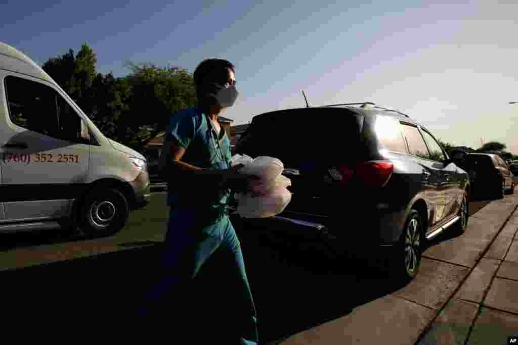 FILE - Dr. Tien Vo carries food for a family quarantining after testing positive for the coronavirus July 23, 2020, in Calexico, Calif.