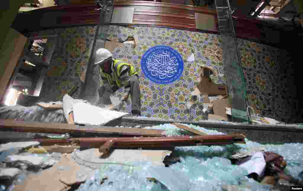 An antiquities restoration worker moves broken glass at the Egyptian National Library and Archives, which was damaged by a car bomb attack targeting the nearby Cairo Security Directorate, Cairo, Jan. 26, 2014.