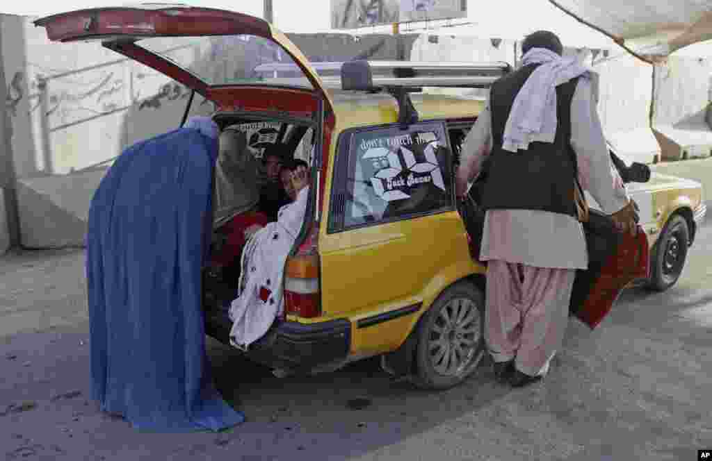 A female police officer, in blue burqa, searches female passengers at a checkpoint in Kandahar, south of Kabul, Afghanistan, June 13, 2014. 