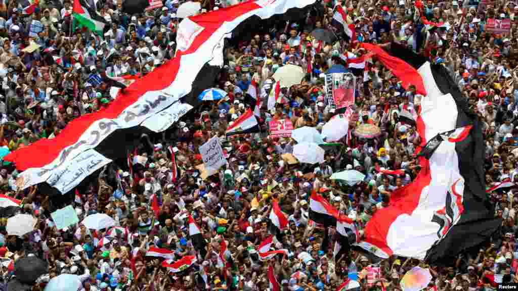 Supporters of the Muslim Brotherhood's presidential candidate Mohamed Morsi stand under giant Egyptian flags during a demonstration against the delay of the Egyptian presidential results at Tahrir Square in Cairo, June 22, 2012.