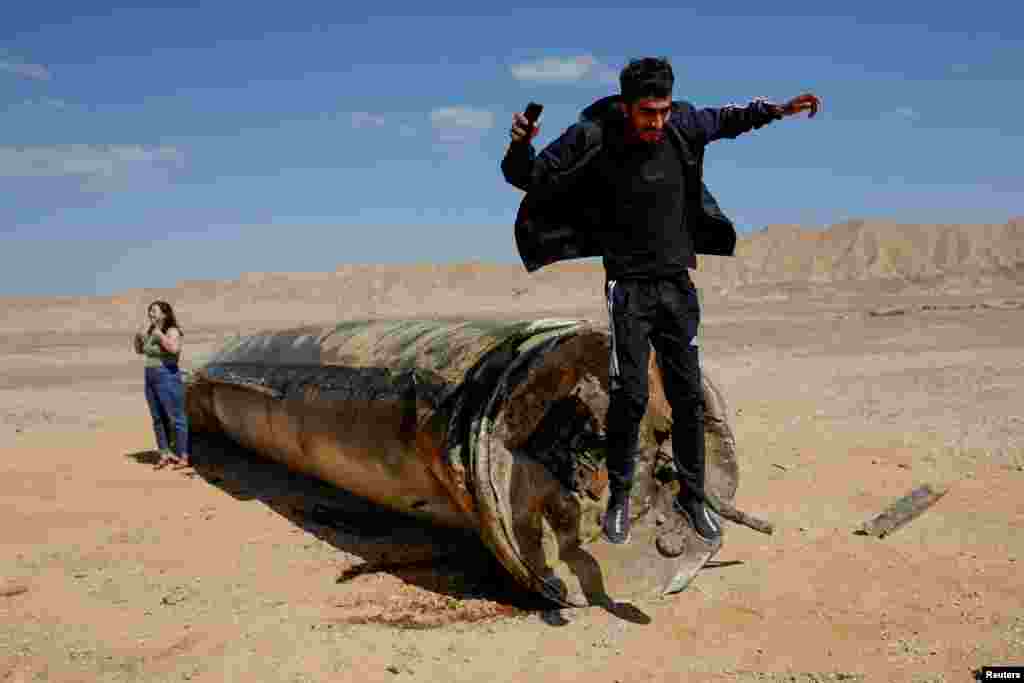A man jumps off apparent remains of a ballistic missile lying in the desert, following an attack by Iran on Israel, near the southern city of Arad, Israel, Oct. 2, 2024.