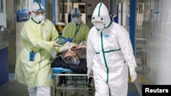 Pekerja medis mengenakan pakaian pelindung memindahkan seorang pasien ke bangsal isolasi rumah sakit di distrik Caidian setelah wabah virus corona baru di Wuhan, provinsi Hubei, Cina 6 Februari 2020. (Foto: dok). 