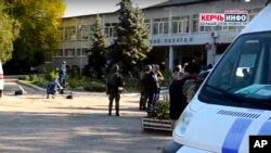 Policemen and investigators stand near a vocational college, in Kerch, Crimea, Oct. 17, 2018, following a shooting rampage.