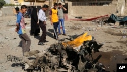 Warga setempat memeriksa lokasi serangan bom mobil di distrik Mashtal, Baghdad, Irak hari Minggu (27/10). 