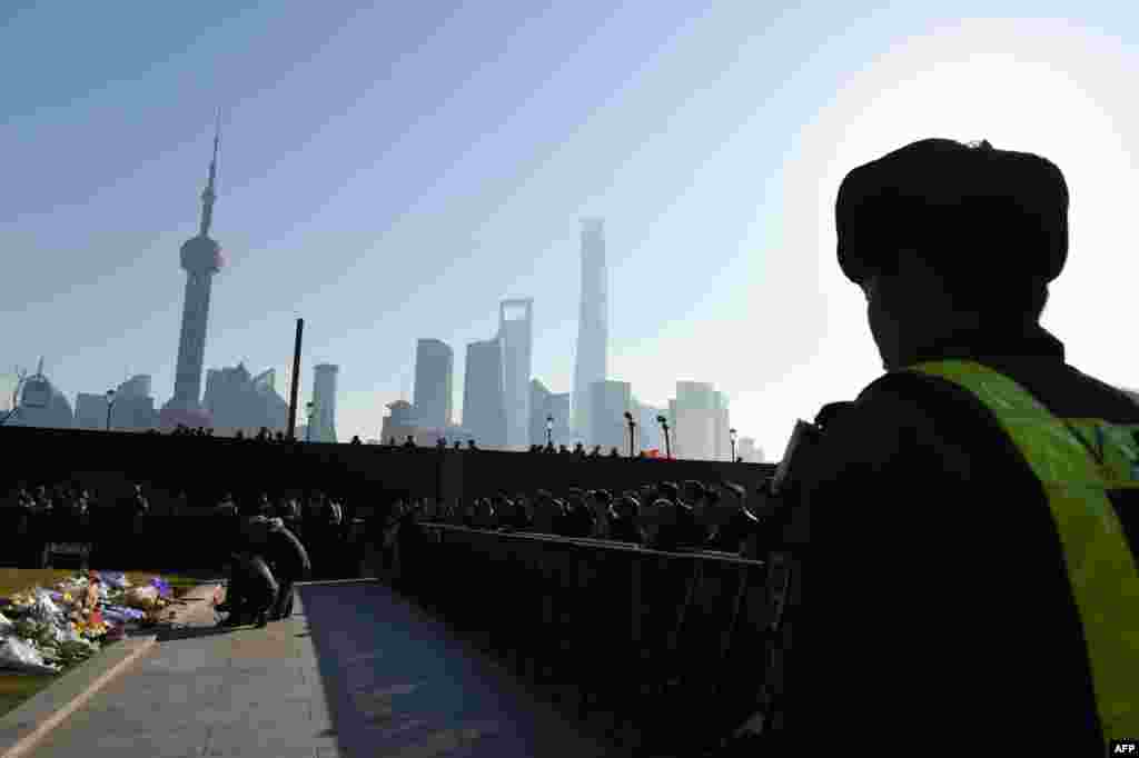Seorang petugas keamanan tampak mengawasi, sementara orang-orang yang berkabung meletakkan bunga dan membakar dupa di lokasipara korban yang tewas terinjak pada malam tahun baru di Bund di Shanghai, China. Bencana malam tahun baru itu terjadi sesaat sebelum tengah malam di wilayah bersejarah di kota itu, menewaskan setidaknya 36 orang. 