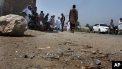 Petugas kepolisian Pakistan dan penduduk loka berkumpul di lokasi insiden penembakan di Garhi Sohbat Khan (18/9). Peshawar, Pakistan. (foto: AP Photo/Mohammad Sajjad)