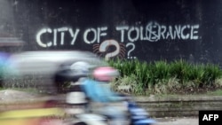 Gambar ini diambil pada tanggal 8 Mei 2016 menunjukkan seorang pengendara yang melewati sebuah grafiti yang menyerukan toleransi di Yogyakarta. (Foto: AFP)
