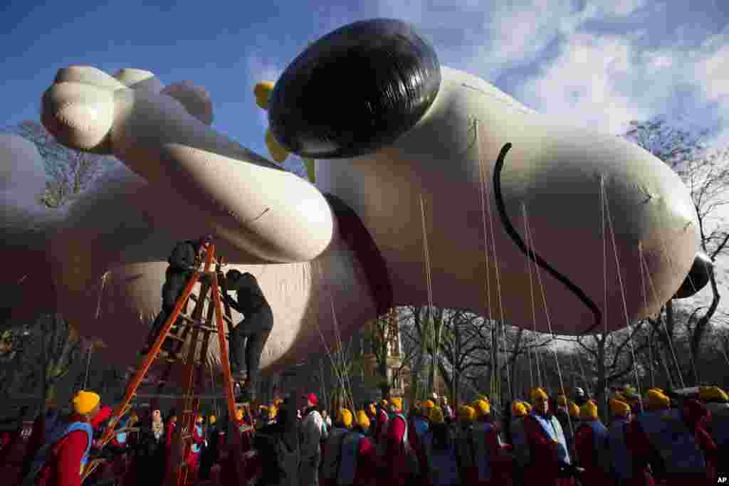 Para pekerja menyiapkan balon Snoopy raksasa sebelum Parade Hari Bersyukur Tahunan Macy's ke-87 di New York (28/11). (AP/John Minchillo)