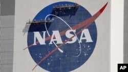 Workers near the top of the 526 ft. Vehicle Assembly Building at the Kennedy Space Center spruce up the NASA logo standing on scaffolds in Cape Canaveral, Fla., Wednesday, May 20, 2020. A SpaceX Falcon 9 rocket scheduled for May 27 will launch a…