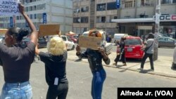 Cidadãos seguram cartazes a dizer “Este país é nosso” e “Juntos contra a corrupção” durante um protesto com buzinas em Maputo, capital de Moçambique. 21 novembro 2024